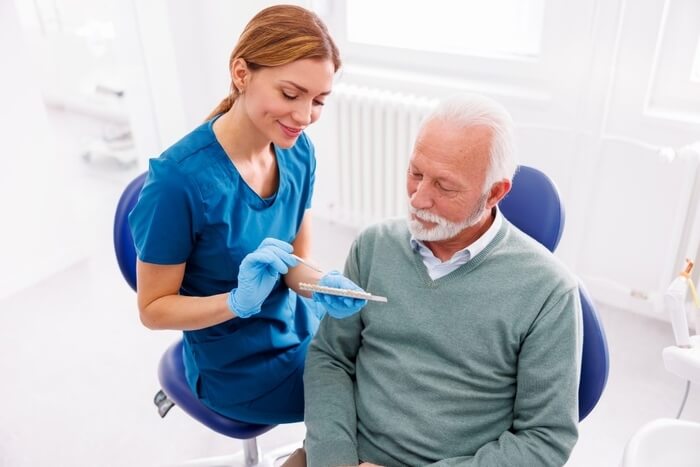 Dentist showing to patient zirconium dental veneers color palette
